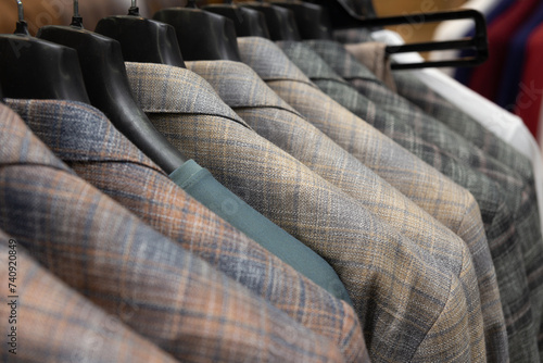 A row of men's suits, jackets hanging on a rack for display.