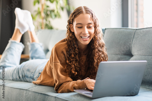 Happy modern adolescent girl enjoys e-learning with laptop at home © Prostock-studio