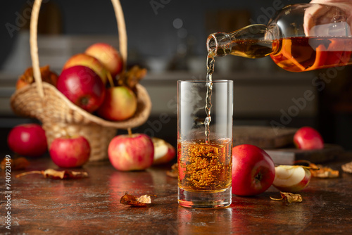 Apple cider is poured from a bottle into a glass. photo