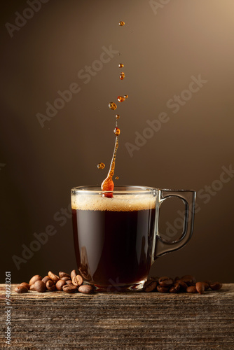 Espresso coffee glass cup with splashes on a brown background.