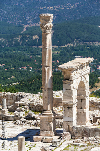 Triumphal arch and honorary column at Upper Agora in ancient city of Sagalassos. Cover page. Scenic landscape of Pisidia at background. Aglasun, Budur, Turkey photo