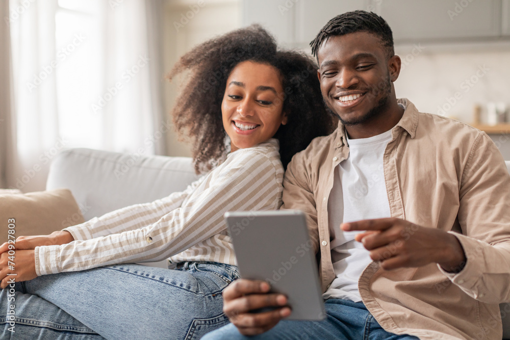 Happy African couple with digital tablet enjoys online content indoor Happy African couple with digital tablet enjoys online content indoor