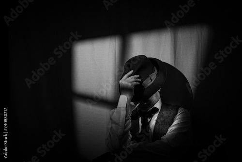 Film Noir style detective wearing a Fedora hat, tie and waistcoat in a dark, seedy office with a stylized window behind. Face partially obscured by the hat brim. photo
