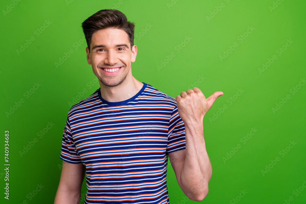 Portrait friendly positive man toothy smile indicate thumb finger empty space news isolated on green color background