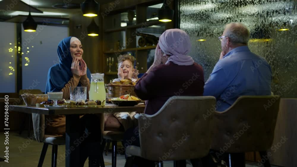 Multigenerational Muslim Family Praying at the Table Before Breaking the Fast in Ramadan Multigenerational Muslim Family Praying at the Table Before Breaking the Fast in Ramadan