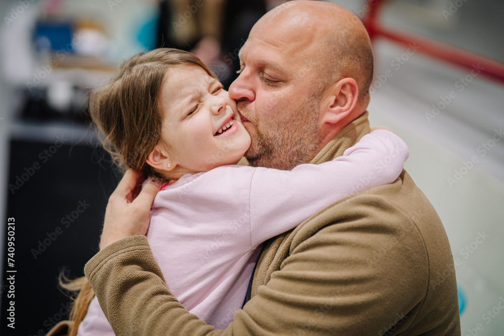 Valmiera, Latvia - February 17, 2024 - a dad kissing a smiling young daughter on the cheek in an affectionate embrace. Valmiera, Latvia - February 17, 2024 - a dad kissing a smiling young daughter on the cheek in an affectionate embrace.