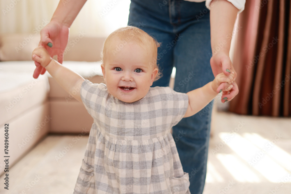 smiling baby boy girl learning to walk with mom, taking first steps with mother helping infant, teaching child at home on floor. The concept of childhood and a happy family. smiling baby boy girl learning to walk with mom, taking first steps with mother helping infant, teaching child at home on floor. The concept of childhood and a happy family.