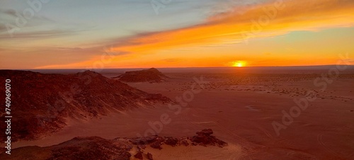Panoramic sunset view from Timimoun, Algeria, overlooking the red sand desert and canyons from a hilltop.