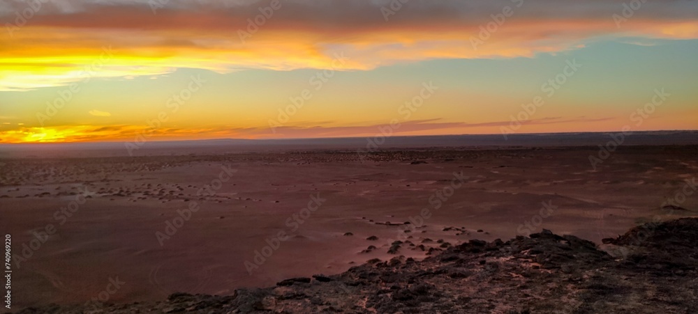 Obraz premium Panoramic sunset view from Timimoun, Algeria, overlooking the red sand desert and canyons from a hilltop.