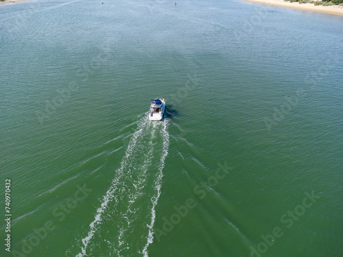 Aerial drone view of a motor boat navigating in the Piedras river between the El Portil beach village and La Flecha sand bank photo