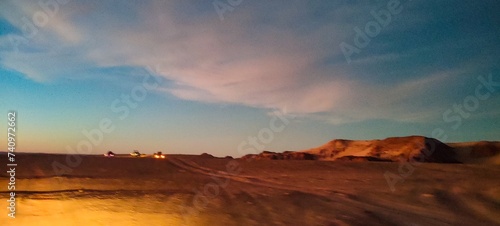 panoramic view over the red sand desert and canyons, crossed by off-road cars at sunset. Timimoun, Algeria