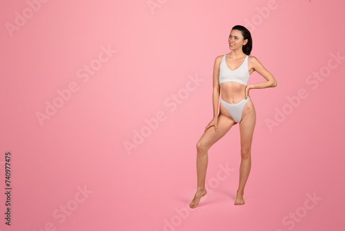 Confident young woman in white underwear posing with one hand on her hip and a leg slightly raised