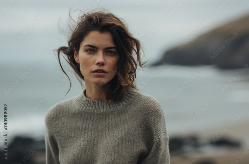 Serene woman in grey sweater by the sea on a windy day. Serene woman in grey sweater by the sea on a windy day.