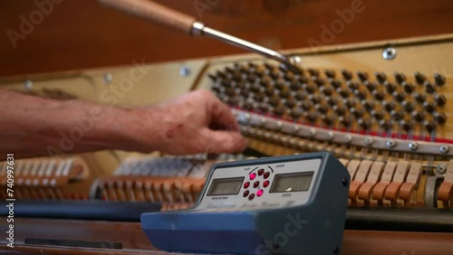 Close-up view of a piano tuner working on an upright piano.  	 photo