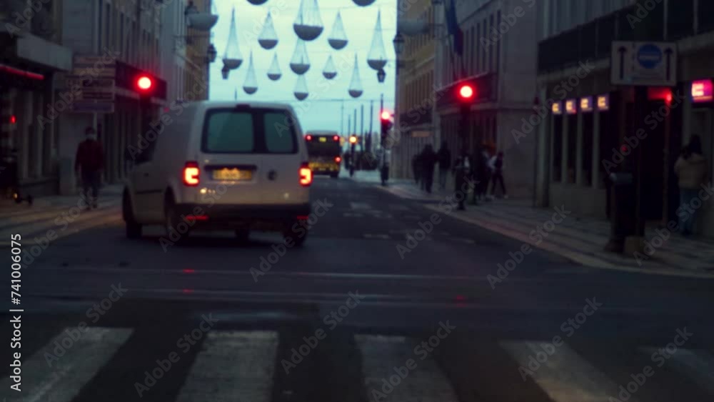 tilt down no meio de uma avenida movimentada com carros, sinais de transito, semaforos e luzes, durante a blue hour. ceu azulado e decorações na rua. Podem ver-se os carros na hora de ponta e pessoas 