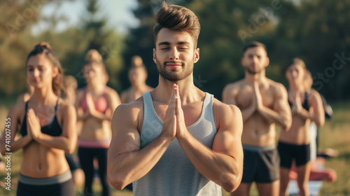 A man in a meditative pose with a group reflects a sense of balance and well-being, encapsulating the spirit of collective mindfulness and the pursuit of inner peace through yoga