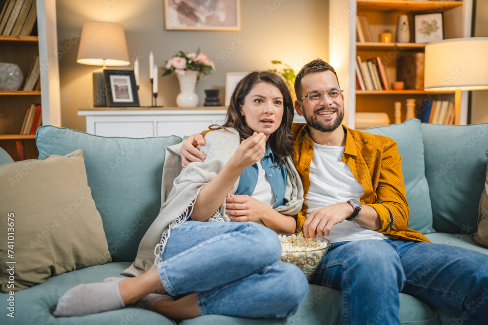 Couple caucasian man and woman sit at home on sofa bed watch tv movie Couple caucasian man and woman sit at home on sofa bed watch tv movie
