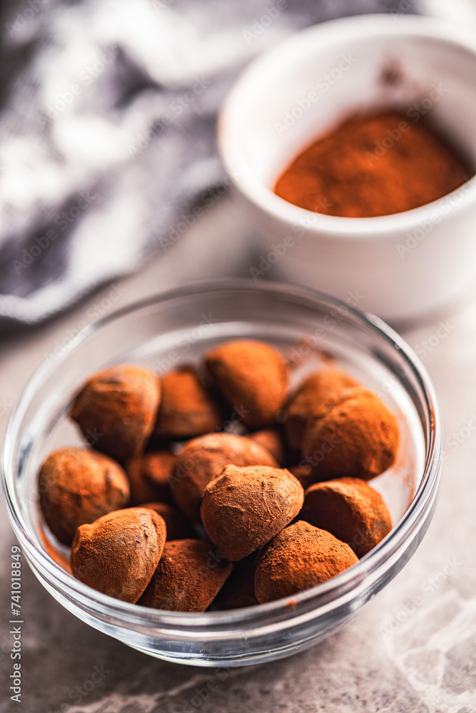 Chocolate truffles covered with cocoa powder in bowl on kitchen table. Chocolate truffles covered with cocoa powder in bowl on kitchen table.
