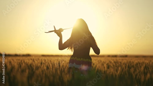 girl with a toy. girl with a toy airplane runs across the field. landscape field at sunset with sun glare. happy family dream content lifestyle photo