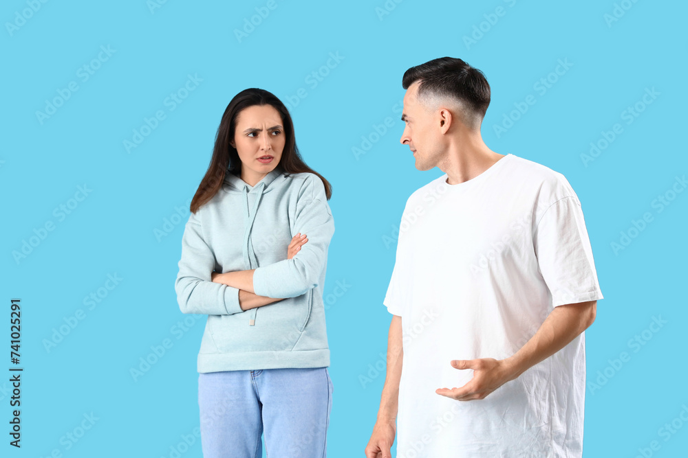 Offended young woman with her husband on blue background Offended young woman with her husband on blue background