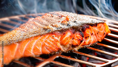 The photo of grilled red fish with light smoke and hot coals