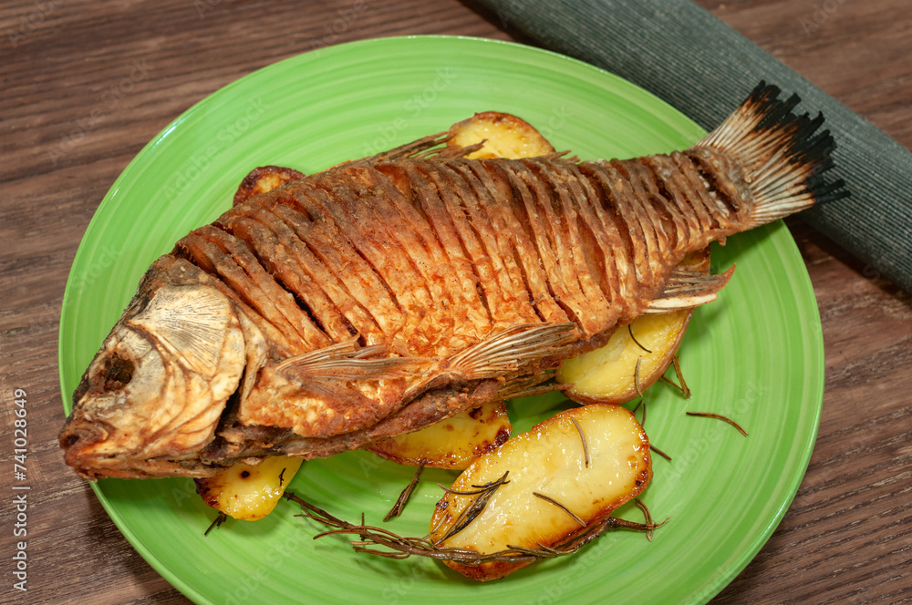 Fried crucian fish on wooden table garnished with potato. Fried crucian fish on wooden table garnished with potato.
