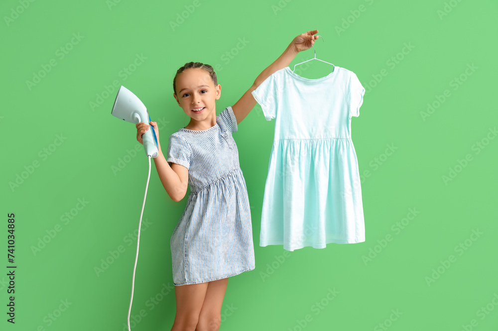 Little girl with steamer and dress on green background Little girl with steamer and dress on green background