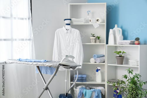 Interior of modern laundry room with ironing board and steamer