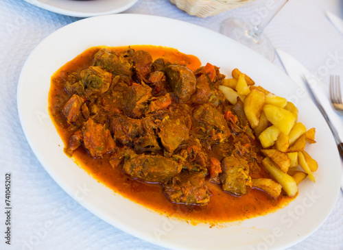 Appetizing baked pork cheeks served with potato and vegetables on plate