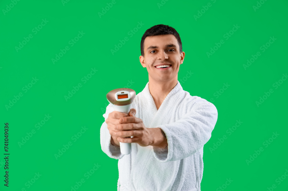 Young man with photoepilator on green background