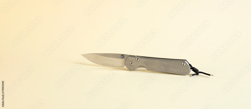 An isolated tourist knife on a beige background. The concept of hunting. An isolated tourist knife on a beige background. The concept of hunting.