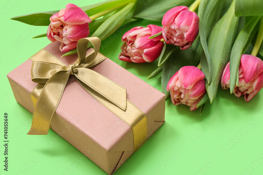 Gift box and bouquet of beautiful tulips on green background. International Women's Day