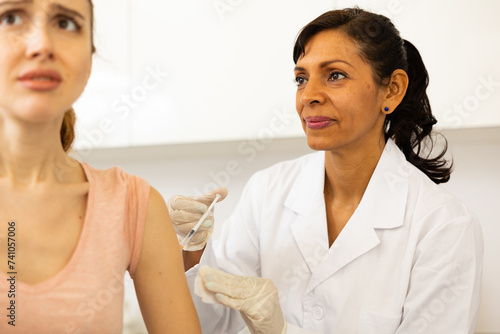 Woman healthcare worker giving injection to patient at doctors office © JackF