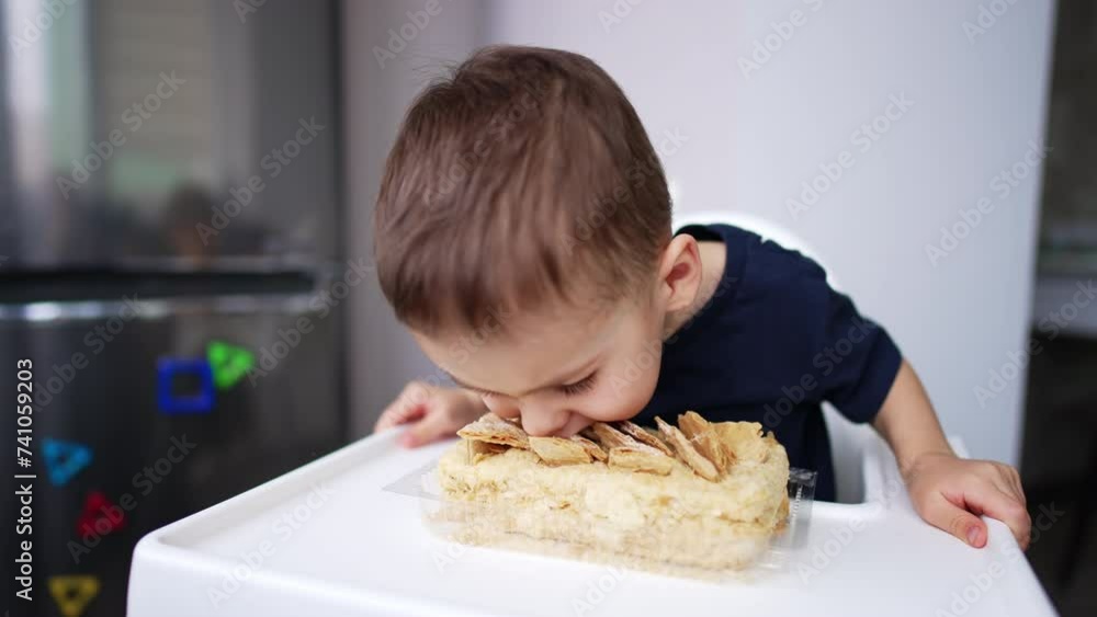 Funny little boy eating a cake using no hands. Toddler bends to the sweet and bites it. Funny little boy eating a cake using no hands. Toddler bends to the sweet and bites it.
