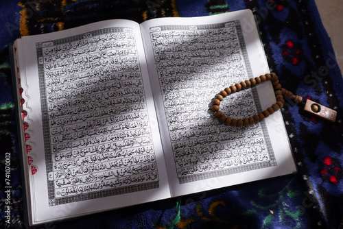 Close-up of wooden prayer beads lying on top of the open Quran photo