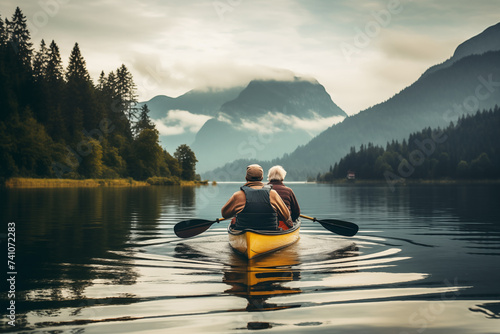 Senior couple kayaking on lake in mountains. Travel and active life concept. Back view photo