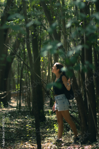 Obraz na płótnie Young woman walking through a forest looking at the sun w salonie