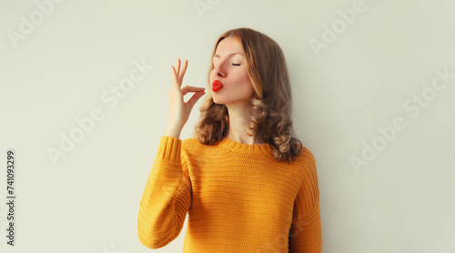Tableau sur toile Happy young woman enjoying perfect flavor, shows gesture of delicious taste of f