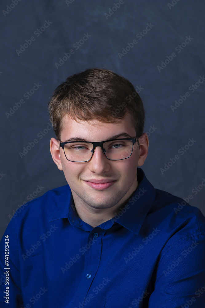 CLOSE UP PORTRAIT OF A WHITE MALE STUDENT WEARING GLASSES AND A BLUE SHIRT. HE IS SMILING LIGHTLY CLOSE UP PORTRAIT OF A WHITE MALE STUDENT WEARING GLASSES AND A BLUE SHIRT. HE IS SMILING LIGHTLY