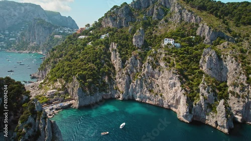 Cliffs on secluded cove with famous Da Luigi ai Faraglioni beach on Capri, italy. Sheer limestone rocks shelter a tranquil azure bay. Summer vacations. photo