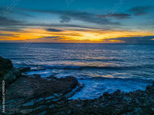 Sunrise over the sea and rock platform with high cloud