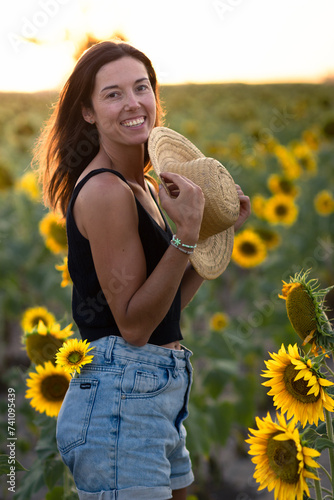 Obraz na płótnie Young smiling woman in a sunflower plantation during golden hour w salonie
