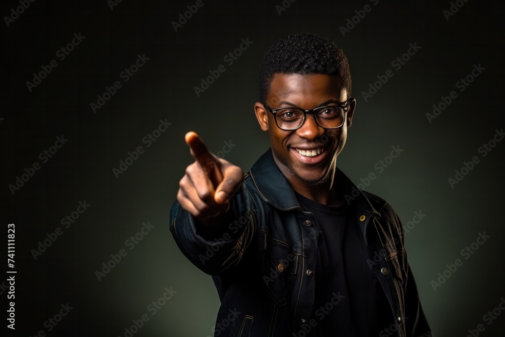 Happy young African American man wearing glasses pointing with index finger on yellow background. Happy young African American man wearing glasses pointing with index finger on yellow background.