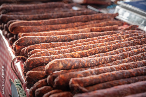 Selective blur on cajna kobasica sausages spiked for sale on a stand of a serbian market. Cajna kobasica, or tea sausage, is a traditional serbian sausage made of smoked cured pork.