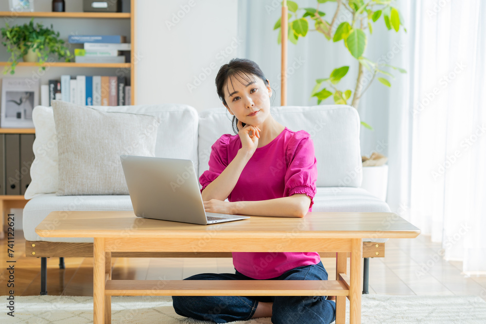 自宅でノートパソコンを操作する若い女性