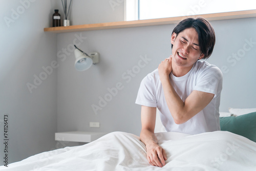 朝寝起きに肩こりに悩む若いアジア人男性（疲労・寝違え・四十肩）
 photo