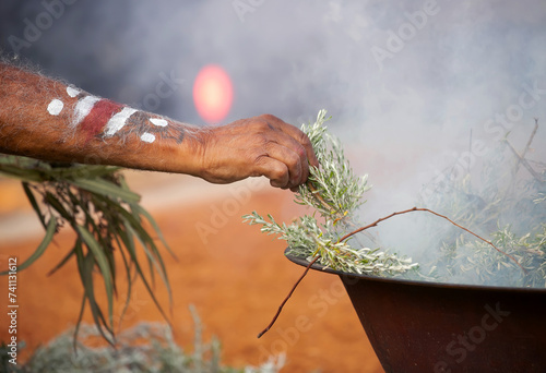 Human hand with green branch of eucalyptus, smoke and fire, the smoke ritual rite at a indigenous community event in Australia photo