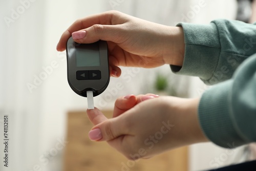 Diabetes. Woman checking blood sugar level with glucometer at home, closeup