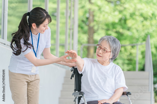 病院・介護施設で腕・肘のリハビリする車椅子に乗る高齢者と介護士（理学療法士・看護師）
