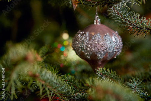 Christmas tree adorned with shiny ornaments lights creating festive ambiance.